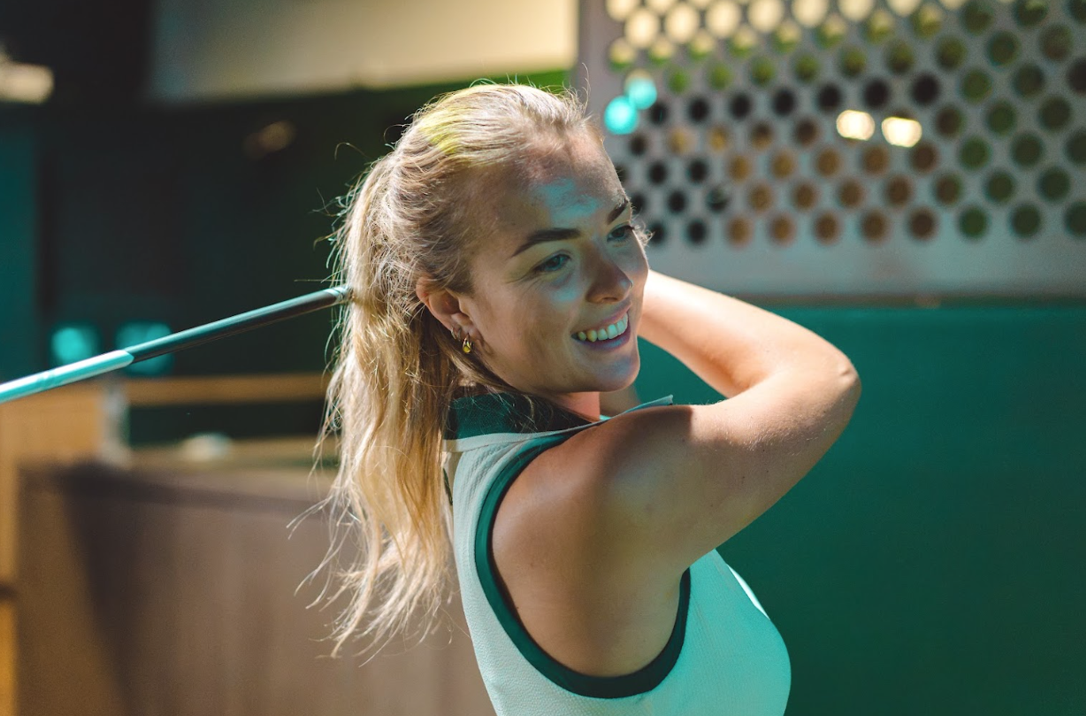 A woman smiling at the finish of her swing at GolfSpace.